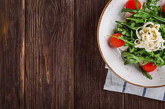 Fresh Arugula Salad with Mozzarella and Tomatoes on Wooden Table