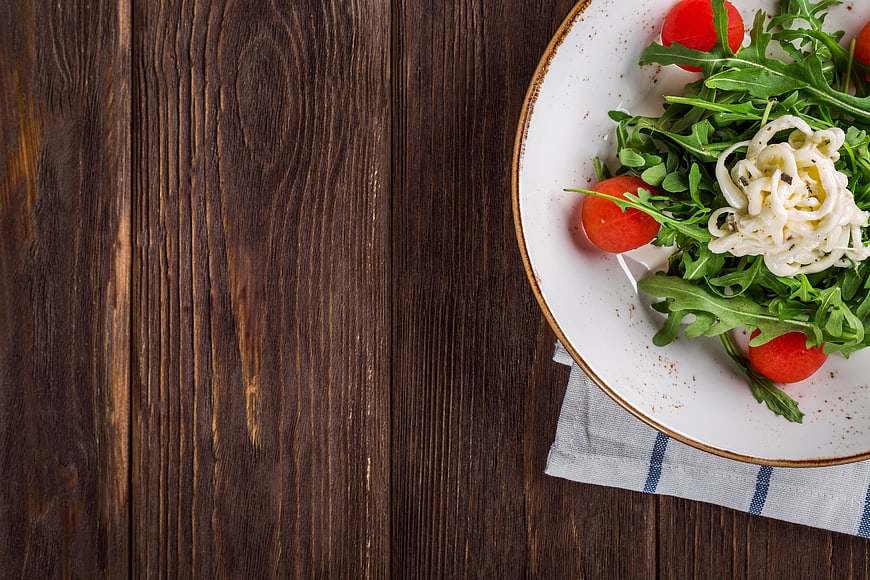 Fresh Arugula Salad with Mozzarella and Tomatoes on Wooden Table
