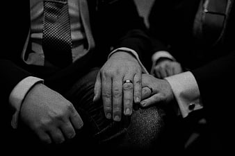 Close-up of groom's hands with wedding ring in black and white