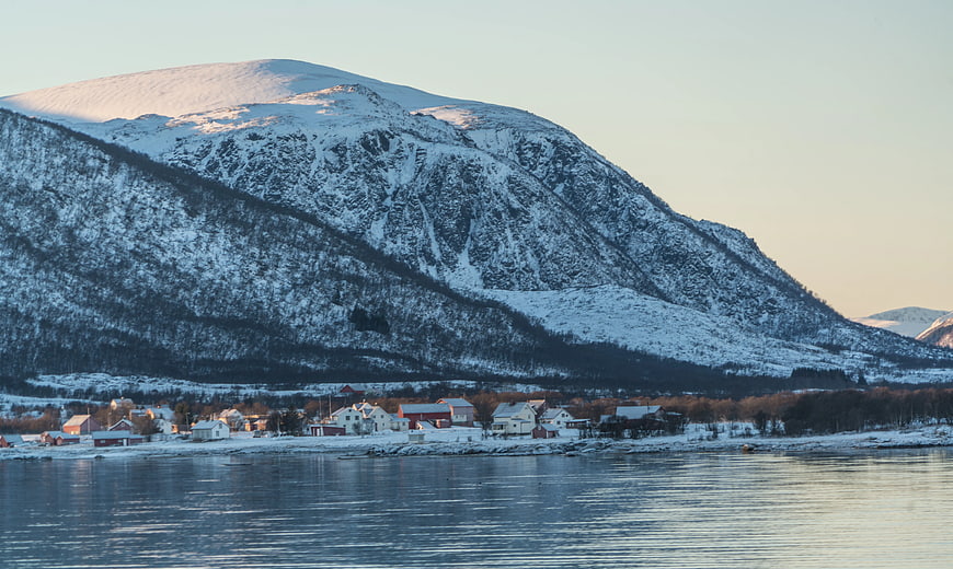 Snow-Covered Mountain Over Coastal Village at Sunset