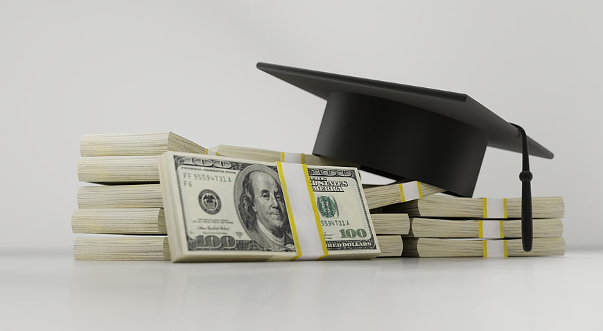 Graduation cap resting on stacks of US hundred dollar bills