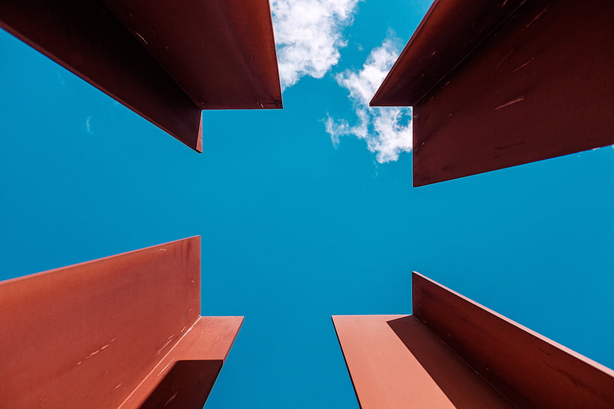 Low angle view of red steel beams against blue sky