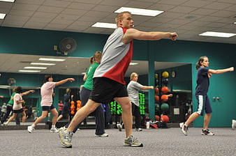 Fitness instructor leading group exercise class in gym
