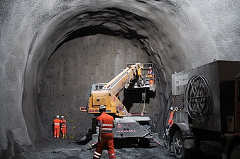Construction workers spraying shotcrete inside a tunnel