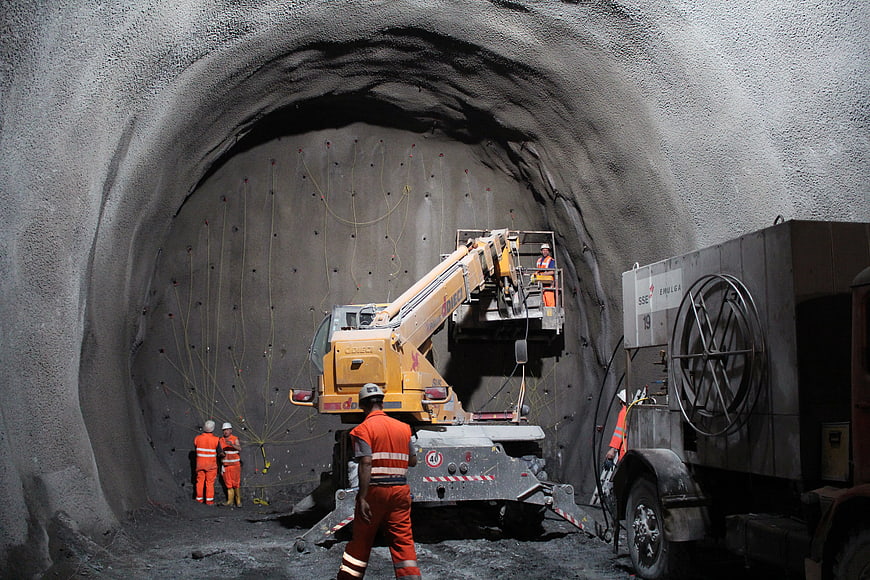 Construction workers spraying shotcrete inside a tunnel