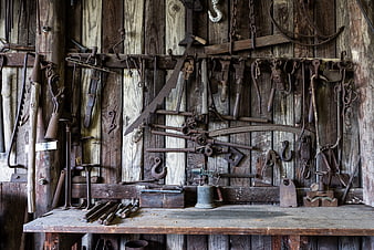 Rusty antique blacksmith tools on rustic wooden workshop wall
