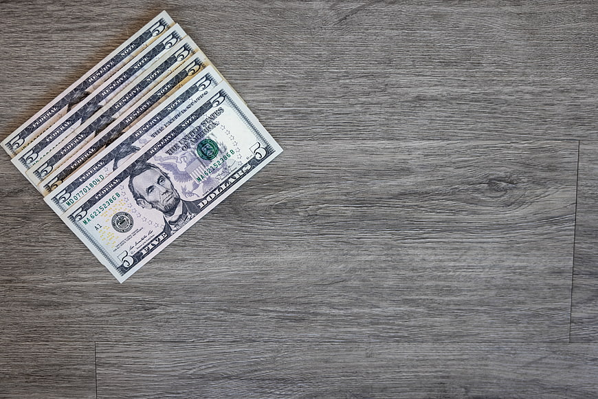 Five Dollar Bills on Gray Wooden Background