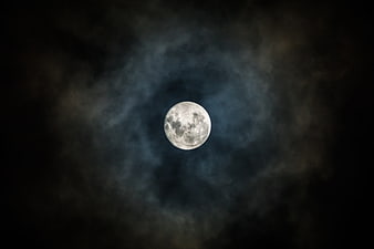 Full Moon Illuminated Through Dark Clouds in Night Sky