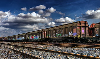 Graffiti Covered Freight Train on Tracks Under Dramatic Sky