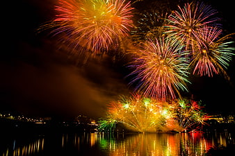 Colorful fireworks exploding over a city river at night