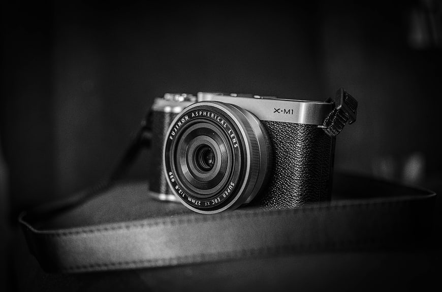 Black and white Fujifilm X-M1 camera on leather strap