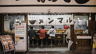 Customers eating ramen at a traditional Japanese restaurant counter