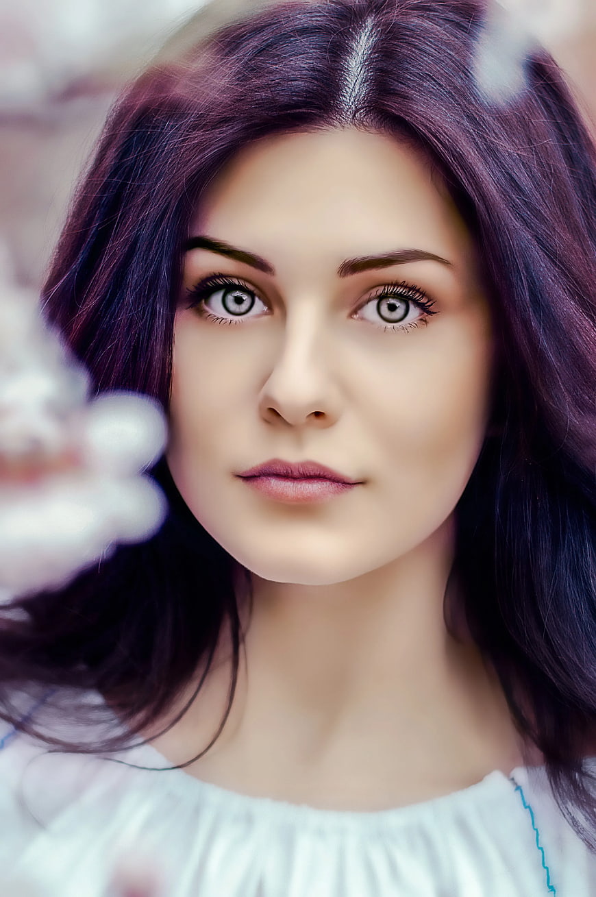 Close-up portrait of woman with purple hair and white eyes