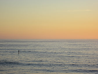 Lone Paddleboarder on Calm Ocean at Sunset