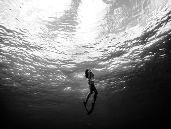 Woman diving underwater in black and white