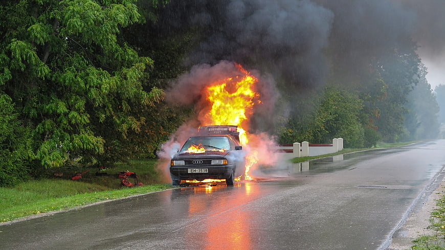 Car on Fire on Wet Road with Smoke