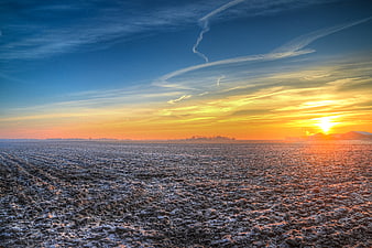 Frosty agricultural field at sunrise with golden sky