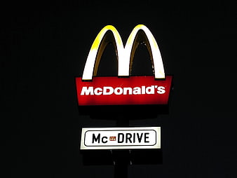 Illuminated McDonald's sign with glowing golden arches and McDrive text at night