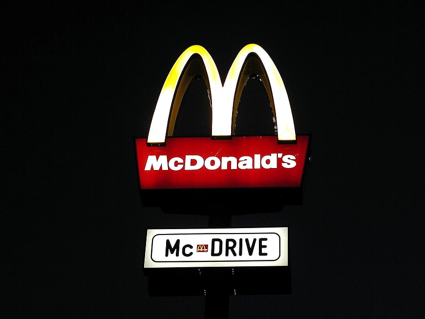 Illuminated McDonald's sign with glowing golden arches and McDrive text at night