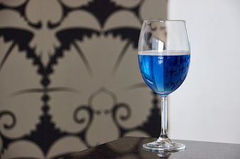 Glass of vibrant blue cocktail on dark table