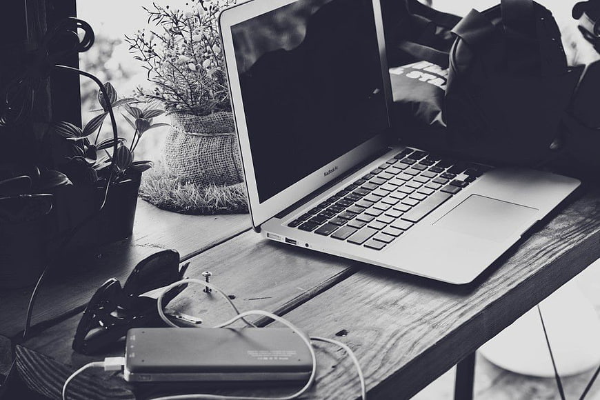 Black and white MacBook Pro on rustic wooden desk
