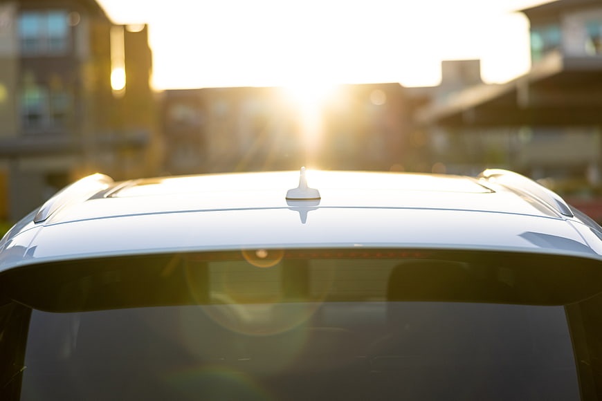 White car roof with antenna in golden hour sunlight