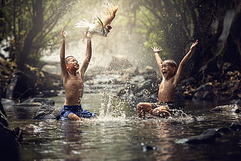 Two Boys Playing With A Bird In A Forest Stream