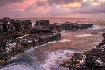 Dramatic Sunset Over Rocky Coastal Cliffs and Ocean Waves