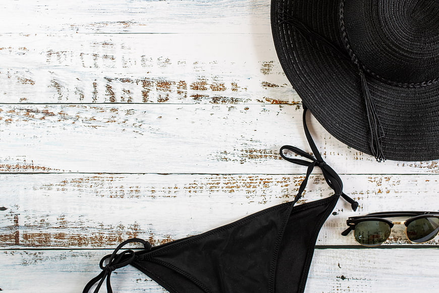 Black Bikini, Sunglasses, and Hat on White Wooden Background
