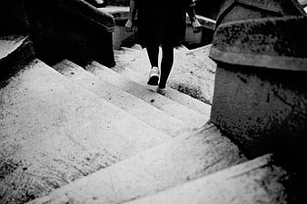 Black and white photo of woman walking up concrete stairs