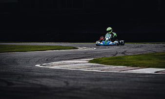 Go-kart racing on a track with green helmet