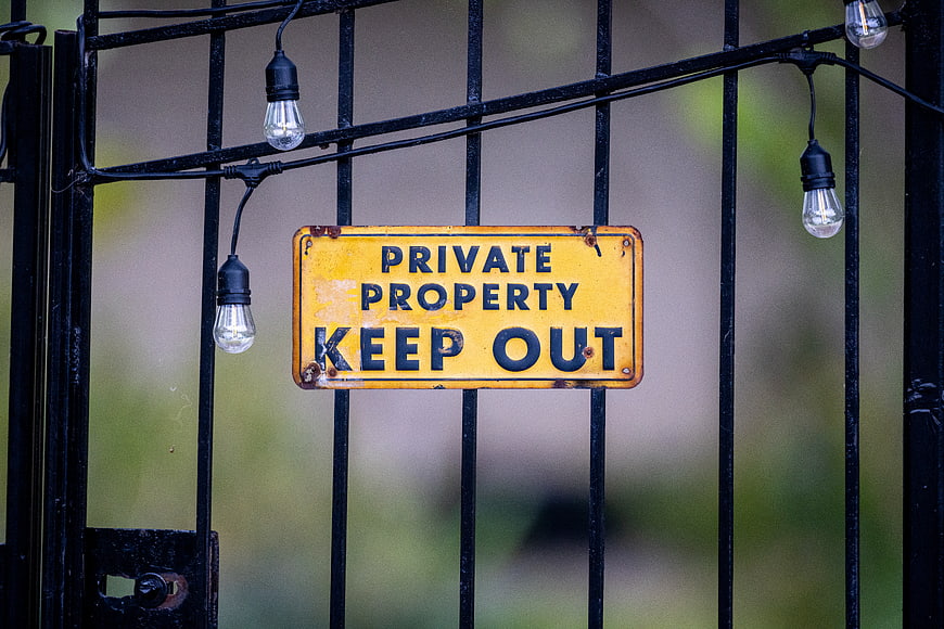 Weathered Private Property Keep Out Sign on Black Metal Gate