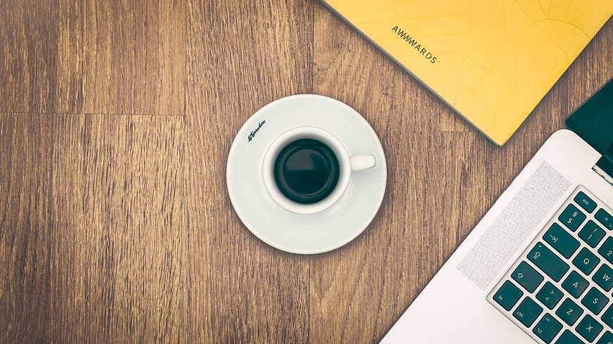 Flat lay workspace with coffee, laptop, and yellow notebook