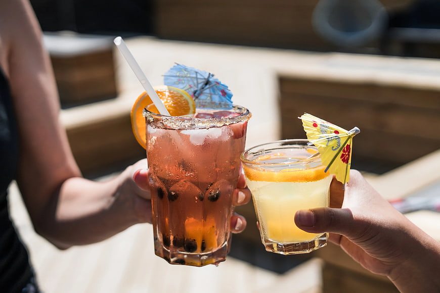 Two Hands Clinking Tropical Cocktails with Umbrellas