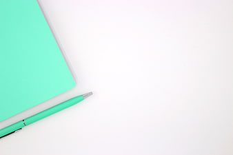Minimalist turquoise notebook and pen on white background