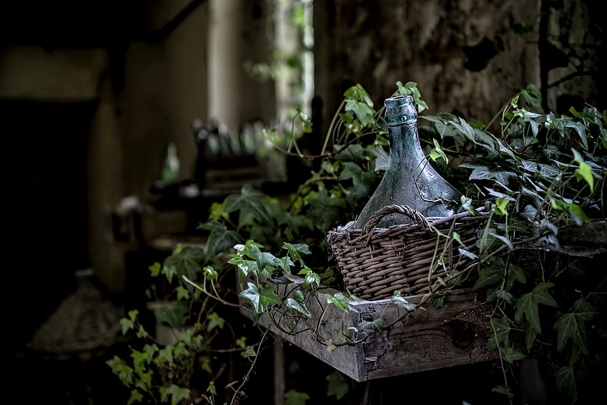 Vintage glass bottle in wicker basket with ivy