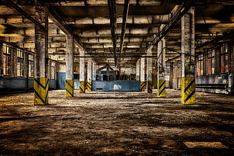 Abandoned industrial factory hall with concrete pillars and yellow stripes