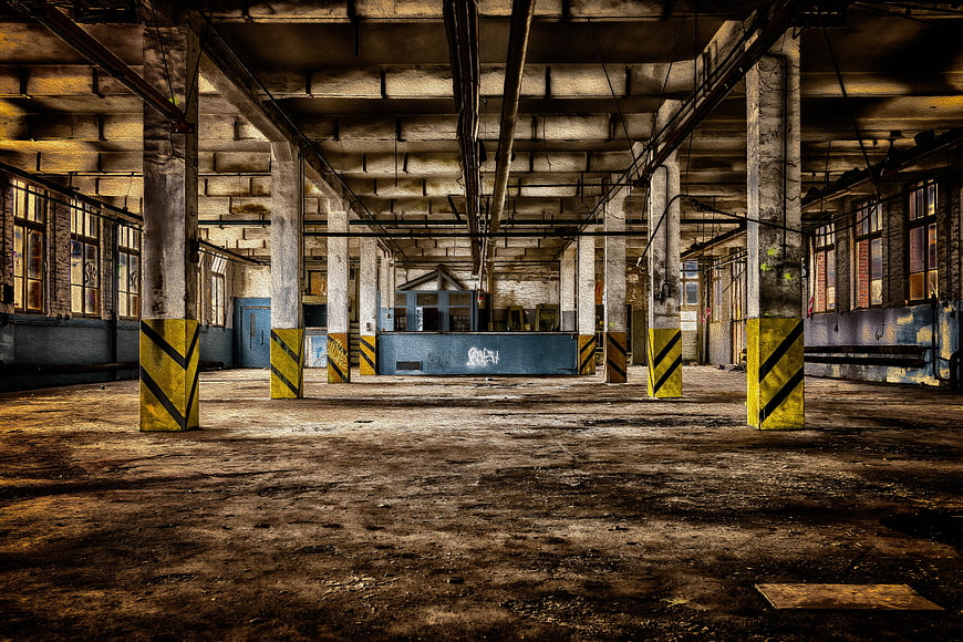 Abandoned industrial factory hall with concrete pillars and yellow stripes
