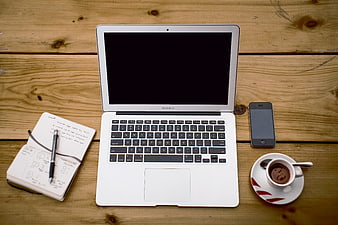 Flat lay of laptop, notebook, coffee, and smartphone on wooden desk