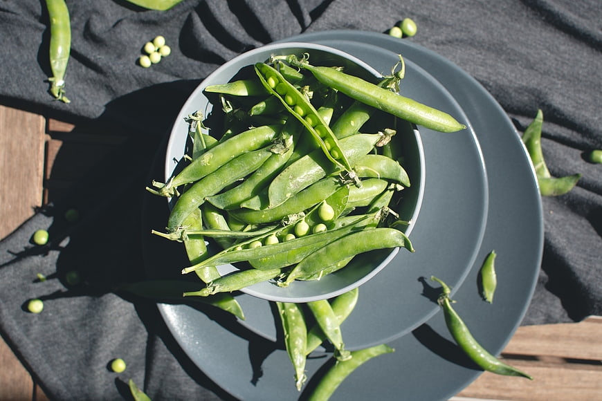 Fresh Green Peas in Bowl on Dark Cloth Top View