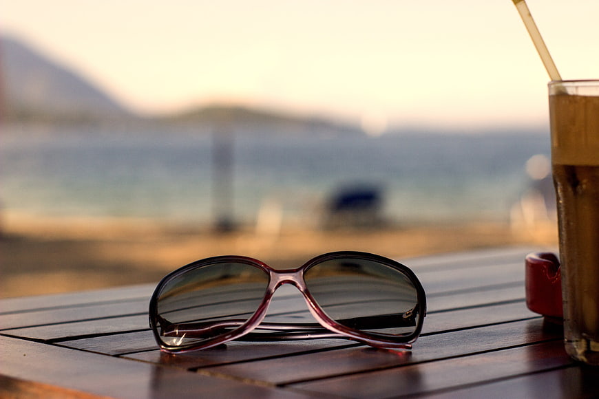 Sunglasses and iced coffee on a beachside table at sunset