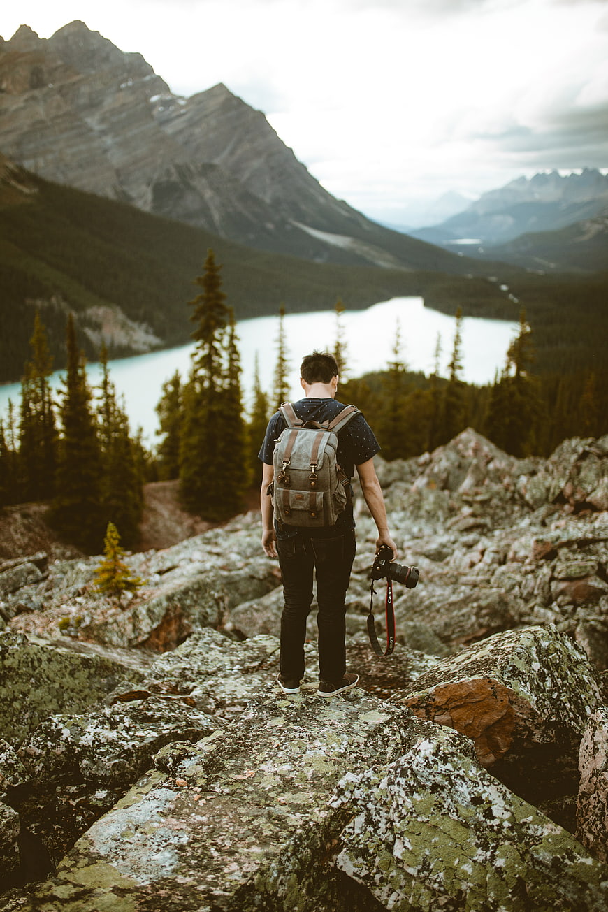 Male Photographer Hiking in Rocky Mountains with Camera