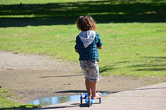 Young boy riding scooter in park