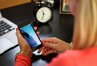Woman using smartphone at office desk with laptop