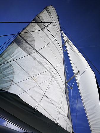 Low angle view of white sailboat sails against blue sky