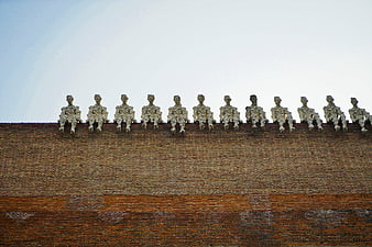 Row of weathered statues sitting on a brick wall