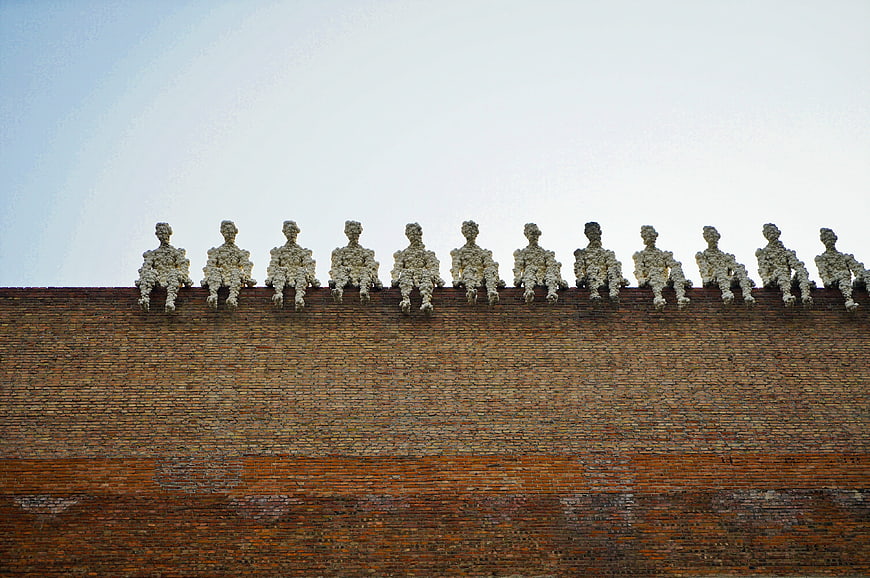 Row of weathered statues sitting on a brick wall