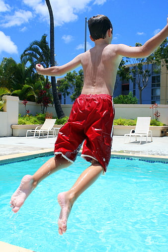 Boy Jumping into Swimming Pool in Red Shorts