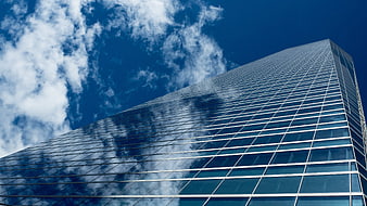 Low angle view of modern glass skyscraper against blue sky
