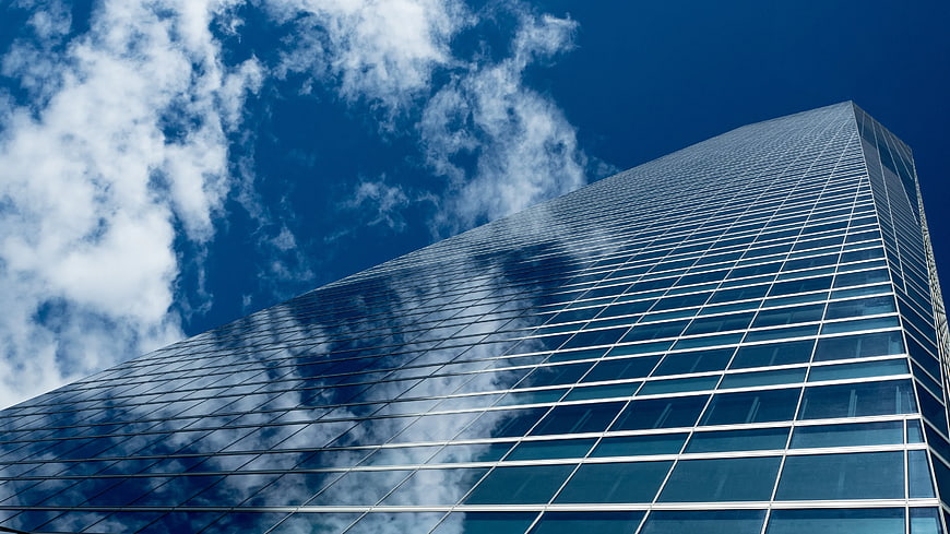 Low angle view of modern glass skyscraper against blue sky